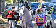 Eine Muslima mit Kopftuch holt ihre zwei Kinder von der Schule ab
