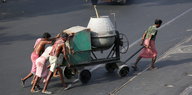 Bauarbeiter ziehen einen Zementmischer über die Straße