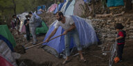 Ein Geflüchteter schaufelt Erde vor einem behelfsmäßigen Zelt auf Samos
