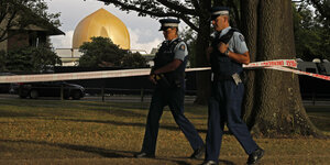 Zwei Polizisten patrouillieren vor einer Moschee mit goldener Kuppel