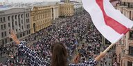 Eine Frau schwenkt in Minsk vor einer großen Menschenmenge die alte weißrussische Fahne