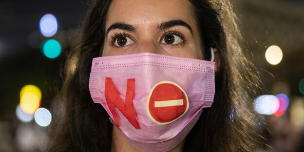 Demonstrantin mit NO-Aufschrift auf MUnd-Nasen-Maske.
