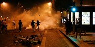 Menschen in Tränengaswolken auf einer spärlich beleuchteten Straße