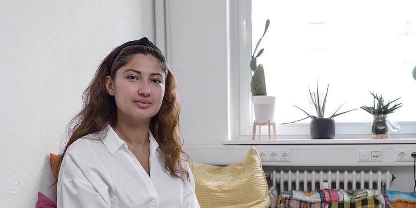 Hila Limar sitzt vor einem Fenster mit Kakteen auf der Fensterbank.