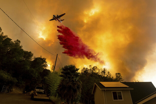 Ein Löschflugzeug wirf Löschmittel über einem Waldbrand ab.