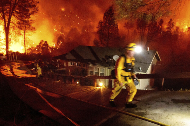 Ein Feuerwehrmann vor einen brennden Wald.