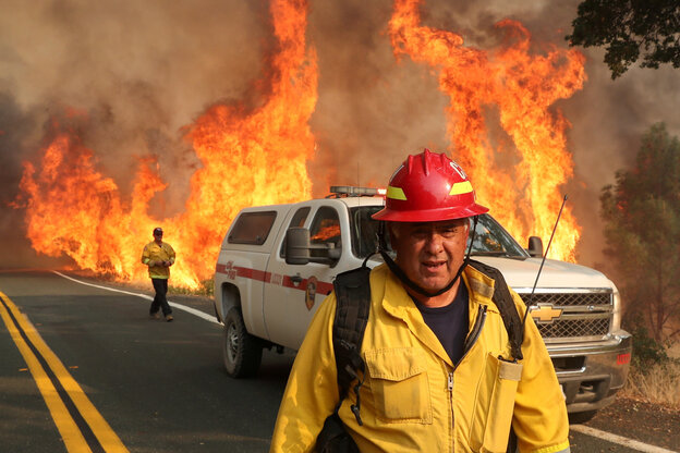 Ein Feuerwehrmann läuft vor einem Hintegrund aus Flammen.