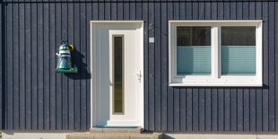 Dunkelbraune hölzerne Hausfassade mit Tür und Fenster