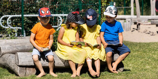 Kindergartenkinder sitzen im garten und lesen in Büchern.