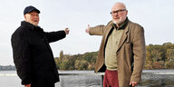 Zwei ältere Männer stehen an einem Geländer und zeigen ins Wasser