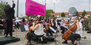 Musiker der Gruppe "Lebenslaute" spielen und singen vor einem Standort des Waffen- und Rüstungskonzerns Rheinmetall.