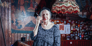 Die Barbesitzerin Rosi Sheridan ist eine alte Frau, die glamourös gekleidet ist und eine Zigarette raucht