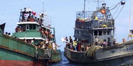 Ein Fischerboot und ein Boot mit Flüchtlingen