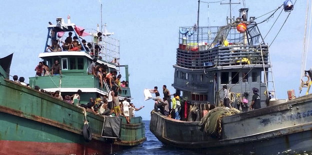 Ein Fischerboot und ein Boot mit Flüchtlingen