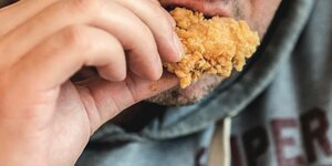 Ein Mann isst ein Hühnerteil