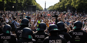 Kette Polizisten vor einer Massenversammlung ohne Masken