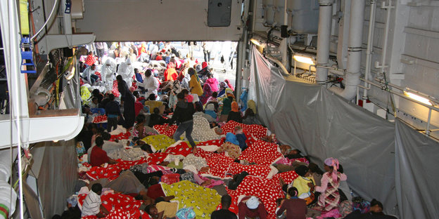 Flüchtlinge sitzen und liegen auf einem Schiff