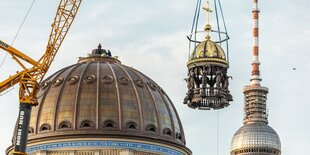 Ein Kran erhebt die christliche Kuppel auf das Stadtschloss. Im Hintergrund der Fernsehturm