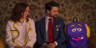 Ellie Kemper (Kimmy Schmidt) und Daniel Radcliffe (Frederick) sitzen neben einem Rucksack mit Gesicht