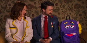Ellie Kemper (Kimmy Schmidt) und Daniel Radcliffe (Frederick) sitzen neben einem Rucksack mit Gesicht