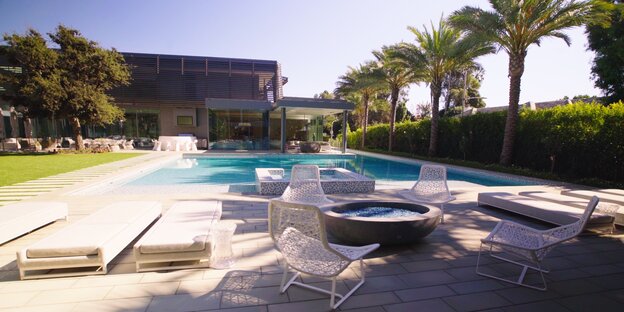 Ein Haus mit Pool, Stühlen und Liegen Ein Haus mit Pool, Stühlen und Liegen