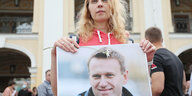 Eine Frau hält ein Porträtfoto von Alexei Nawalny in den Händen
