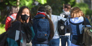 Schulkinder von hinten, ein Mädchen mit Maske dreht sich um