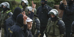 Ein Demonstrant zeigt ein Siegeszeichen während eines Protests vor Polizisten