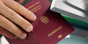 Ein Mann hält seinen Reisepass in eine automatische Passkontrolle
