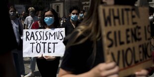 Eine Frau mit mit einem Demoschild. Darauf steht: Rassismus tötet.