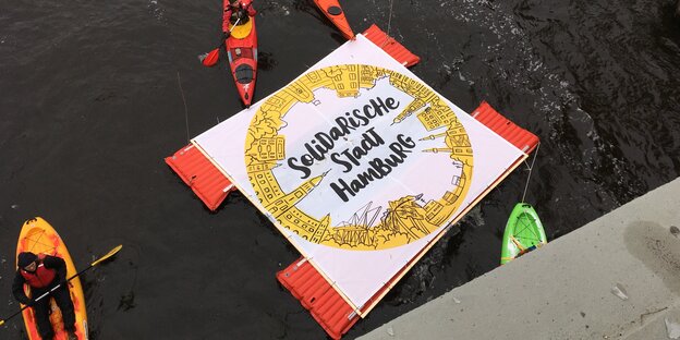 Mit einem schwimmenden Transparent fordert das Bündnis "Solidarische Stadt Hamburg", dass die Stadt Geflüchtete aufnimmt