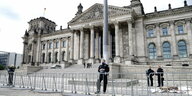 Polizeibeamte sichern hinter Absperrzäunen das Reichstagsgebäude.