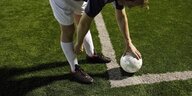Ein Ball liegt auf der Markierung auf einem Fussballfeld mit Kunstrasennem Fußball.