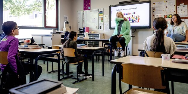 Eine Lehrerin zeigt, wie ind en ellbogen genießt werden soll in einem Klassenzimmer
