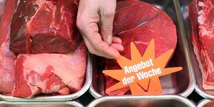 Eine Hand hält ein Schild mit der Aufschrift "Angebot der Woche" an einer Fleischtheke