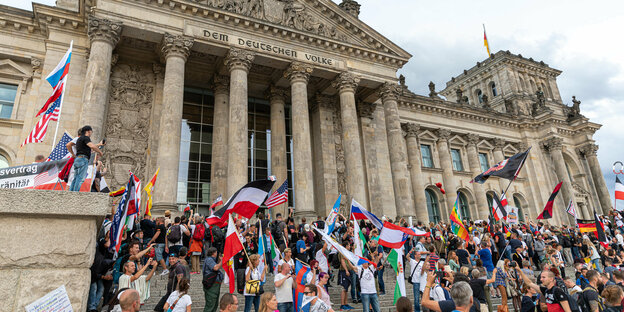 Menschen mit Reichsflaggen stehen vor dem Reichstag