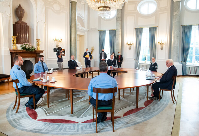 Mehrere menschen sitzen an einem Tisch mit Bundespräsident Steinmeier