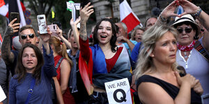 Eine Menschenmenge, Menschen halten Smartphones hoch, ein macht ein Herz-Zeichen mit den Händen, eine trägt ein Plakat mit dem Buchstaben "Q" für die Qanan-Bewegung