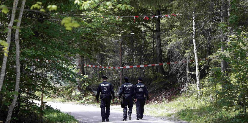 Polizisten von hinten auf einem Waldweg