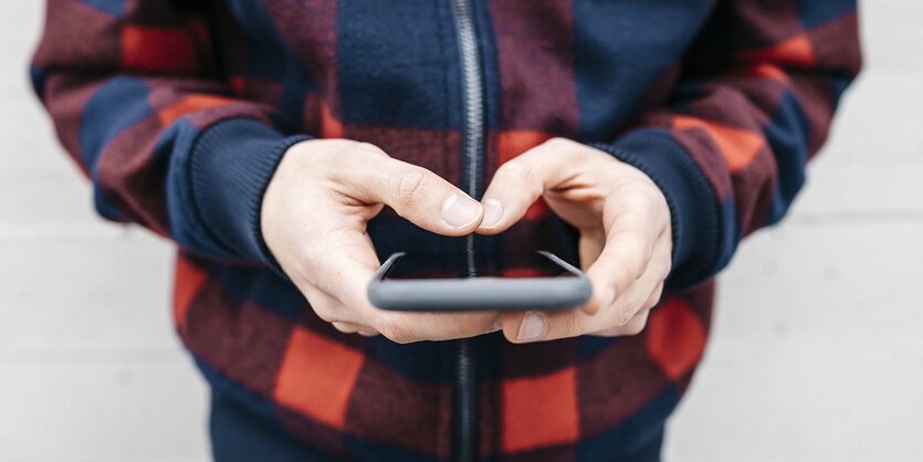 Ein Mann hält ein Smartphone in den Händen