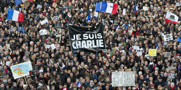 Menschenmassen mit französischen Fahnen und einem Schild mit der Aufschrift "Je suis Charlie"