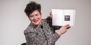 Nora Gomringer hält ein Buch hoch