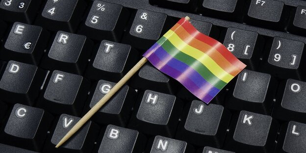Ein Regenbogenfähnchen liegt auf einer Computertastatur