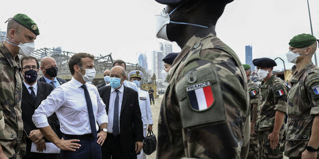 Macron umringt von mehreren Männern, einige tragen Uniform