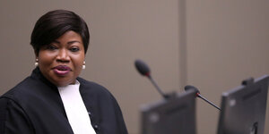 Fatou Bensouda sitzt in einem Gerichtssaal vor einem Mikrofon und lächelt.