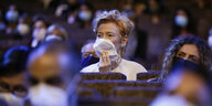 Tilda Swinton sitzt im Publikum in einem Kinosaal und trägt eine Mundschutzmaske