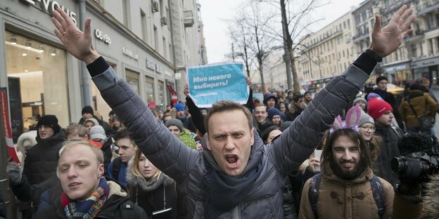 Alexei Nawalny steht in einer Menschenmenge und reißt die Arme hoch