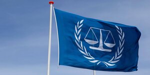 Eine Fahne mit dem UNO-Emblem und einer Waage als Symbol für die Justiz