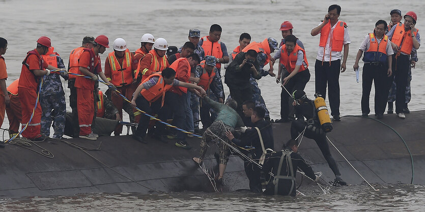 Seenotretter stehen auf einem gekentertem Boot