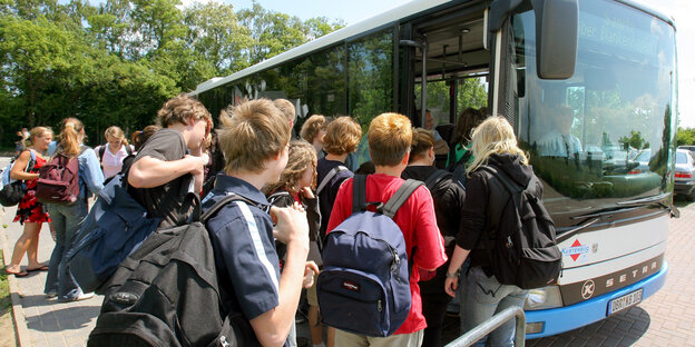 Vor dem Gymnasium in Sanitz bei Rostock steigen Schüler in den Bus, der sie wieder nach Hause bringen soll.
